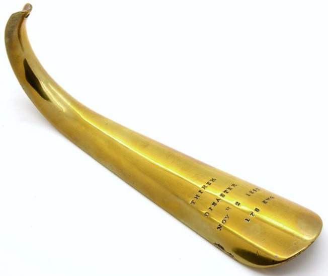 Photograph of a brass shoehorn made from remnants of the train carriages